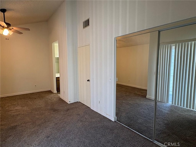 interior space with ceiling fan, a closet, a textured ceiling, and dark colored carpet