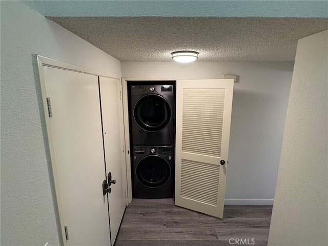 laundry room with stacked washing maching and dryer, dark wood-type flooring, and a textured ceiling