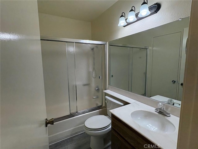 full bathroom with toilet, wood-type flooring, vanity, and shower / bath combination with glass door