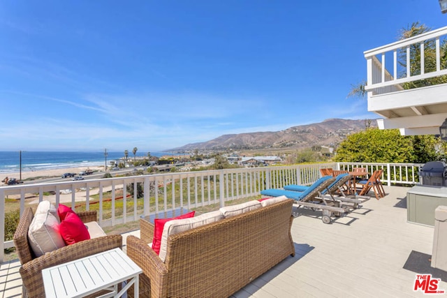 wooden terrace with area for grilling, a water and mountain view, and an outdoor hangout area