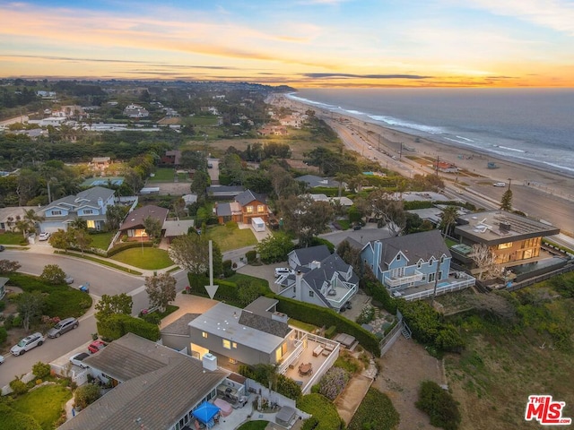 aerial view at dusk featuring a water view