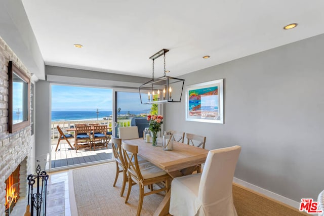 dining space with a fireplace, a water view, and a notable chandelier