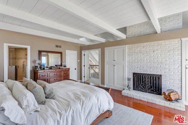 bedroom featuring access to exterior, hardwood / wood-style floors, beamed ceiling, and a fireplace