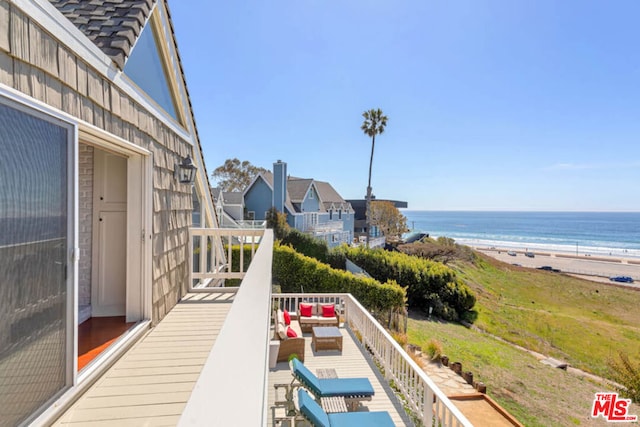 balcony with a view of the beach, a water view, and an outdoor living space