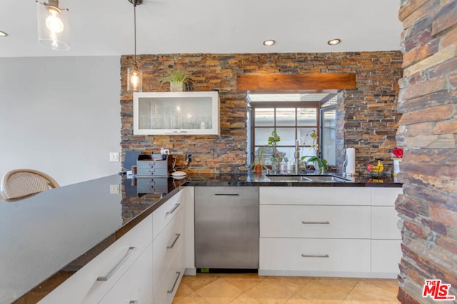 kitchen featuring decorative light fixtures, white cabinets, dark stone counters, and sink