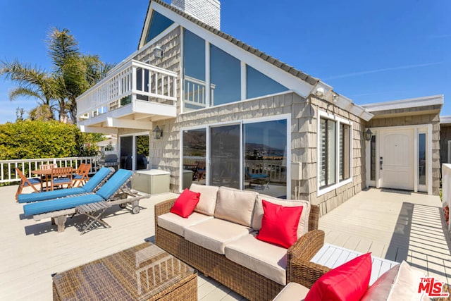 rear view of house with a balcony, outdoor lounge area, and a deck