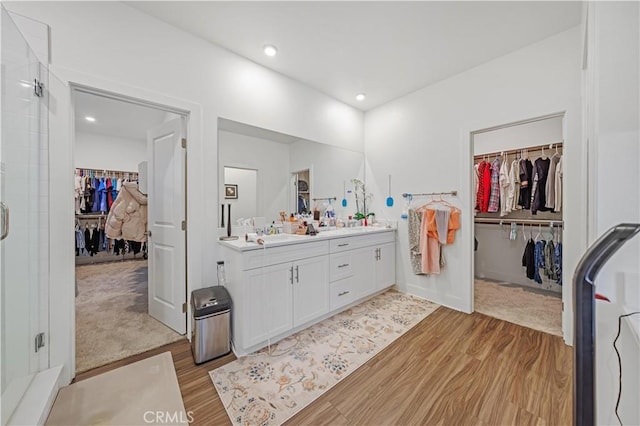 bathroom featuring hardwood / wood-style floors, walk in shower, and vanity