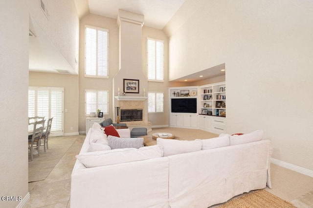 living room with a towering ceiling, built in shelves, light tile patterned floors, and a premium fireplace