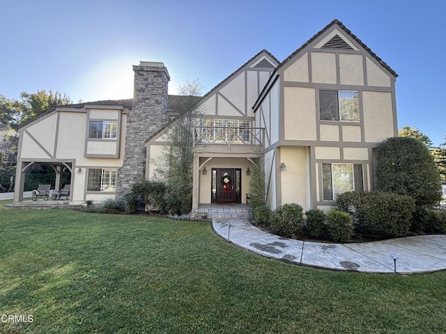 english style home with a front lawn and a balcony