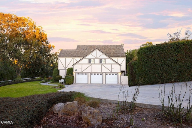 english style home featuring a garage and a yard