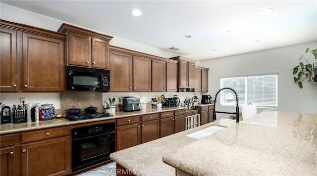 kitchen featuring black appliances, sink, and light stone counters