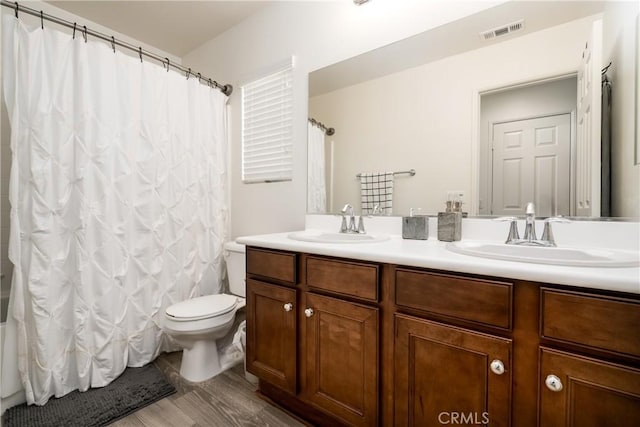 full bathroom featuring toilet, shower / bathtub combination with curtain, hardwood / wood-style flooring, and vanity