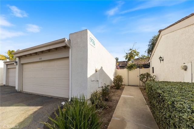 976 E Ln Habra Blvd Unit 115, La Habra, CA 90631 - view of property exterior featuring stucco siding, fence, and a garage