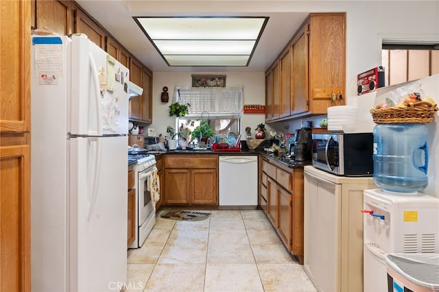 976 E Ln Habra Blvd Unit 115, La Habra, CA 90631 - kitchen featuring dark countertops, white appliances, brown cabinetry, under cabinet range hood, and light tile patterned floors