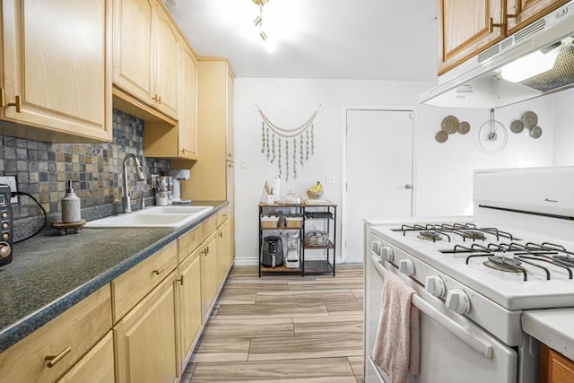 kitchen featuring backsplash, light brown cabinets, white gas range oven, and sink