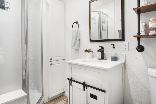 bathroom featuring hardwood / wood-style flooring, an enclosed shower, vanity, and toilet