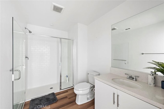 bathroom featuring hardwood / wood-style flooring, an enclosed shower, vanity, and toilet