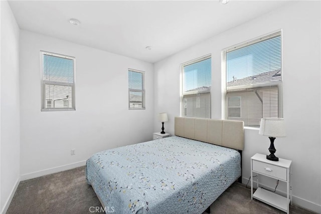 bedroom featuring dark carpet and multiple windows