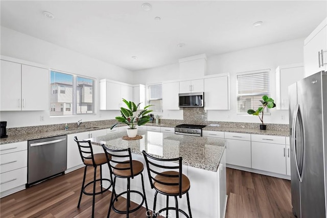 kitchen featuring appliances with stainless steel finishes, a kitchen island, white cabinetry, dark hardwood / wood-style flooring, and sink