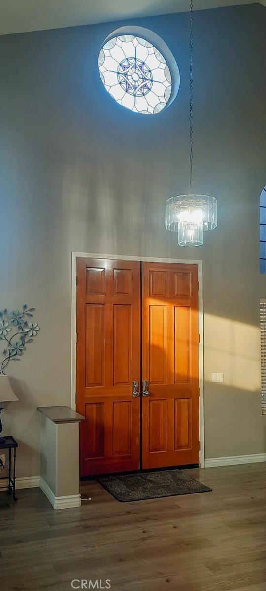 foyer entrance featuring a high ceiling, dark hardwood / wood-style floors, and an inviting chandelier