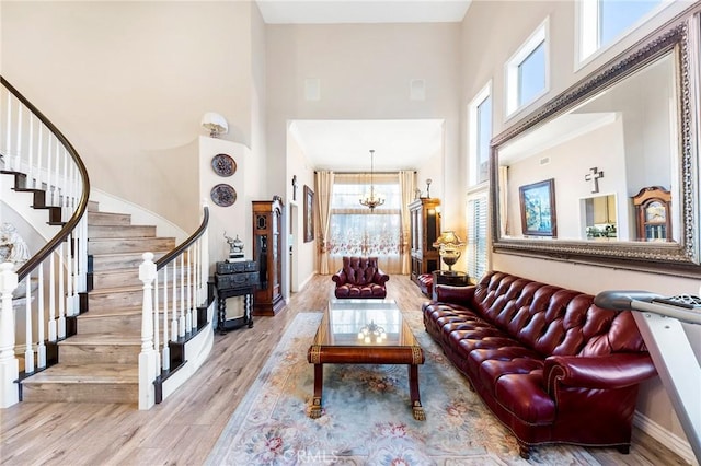 living room with a notable chandelier, plenty of natural light, a high ceiling, and light hardwood / wood-style floors