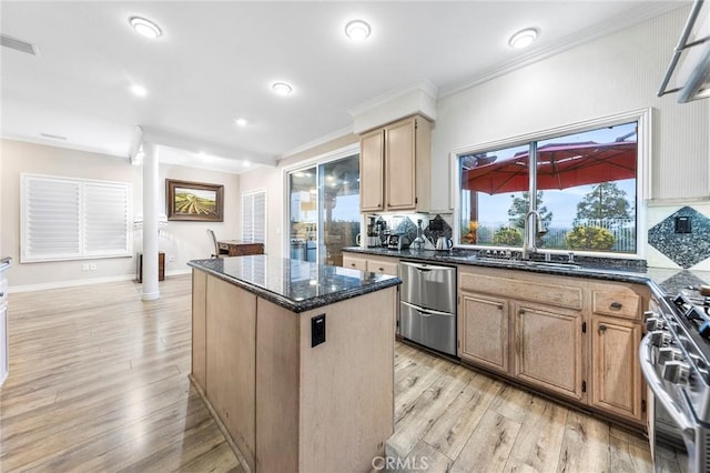 kitchen with appliances with stainless steel finishes, a center island, dark stone counters, light hardwood / wood-style floors, and sink