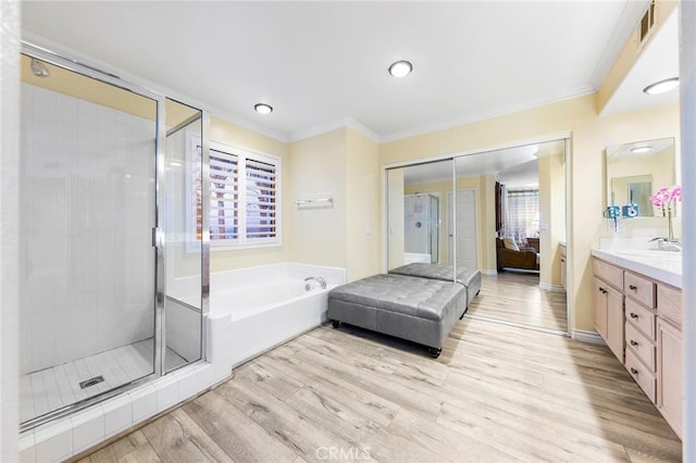 bathroom with a wealth of natural light, wood-type flooring, vanity, and ornamental molding