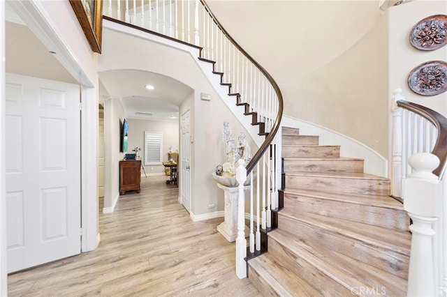 stairway with hardwood / wood-style floors and a towering ceiling