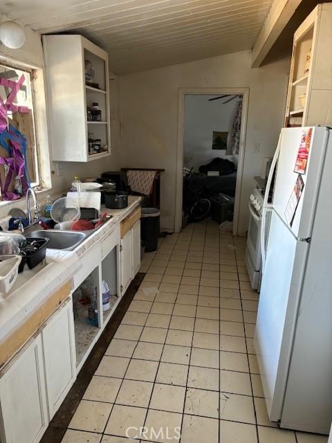 kitchen featuring white appliances, white cabinets, tile counters, vaulted ceiling, and light tile patterned floors