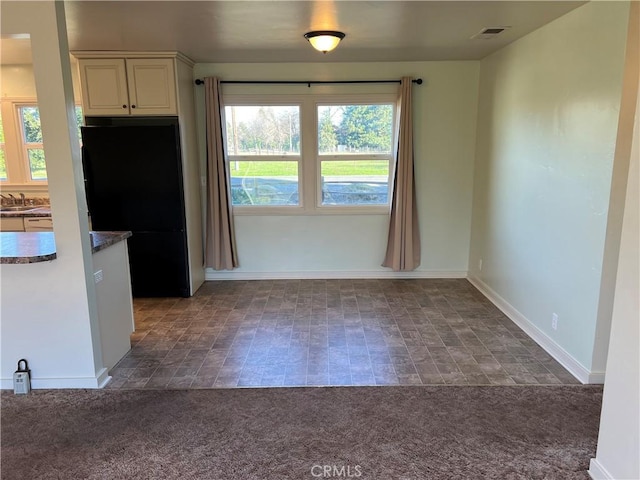 kitchen with black refrigerator, white cabinetry, sink, and dark colored carpet