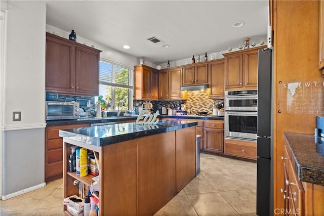 kitchen featuring a kitchen island, sink, light tile patterned floors, stainless steel double oven, and dark stone counters