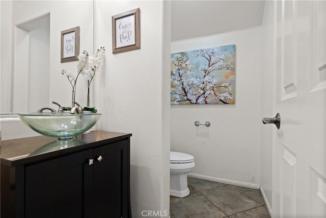 bathroom with toilet, vanity, and tile patterned flooring