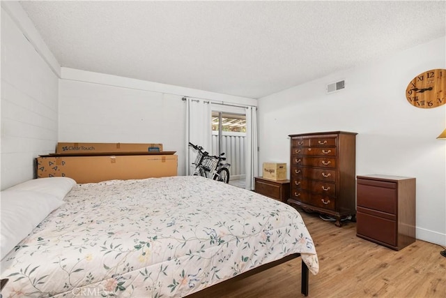 bedroom featuring light hardwood / wood-style floors and a textured ceiling