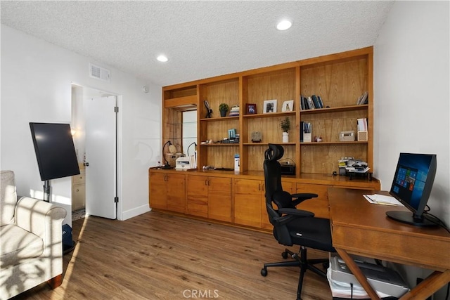 home office featuring wood-type flooring and a textured ceiling