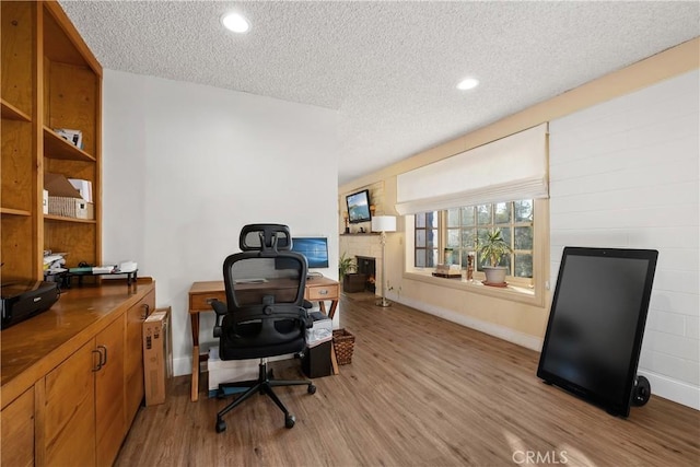 office area with a textured ceiling and light hardwood / wood-style flooring