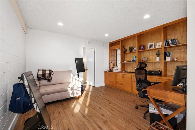 home office with a textured ceiling and hardwood / wood-style flooring