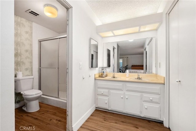 bathroom featuring a textured ceiling, an enclosed shower, vanity, toilet, and hardwood / wood-style flooring