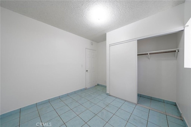 unfurnished bedroom featuring light tile patterned floors, a closet, and a textured ceiling