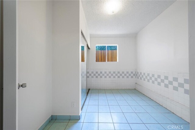 tiled spare room with tile walls and a textured ceiling