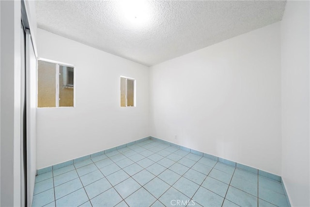 spare room featuring a textured ceiling and light tile patterned flooring