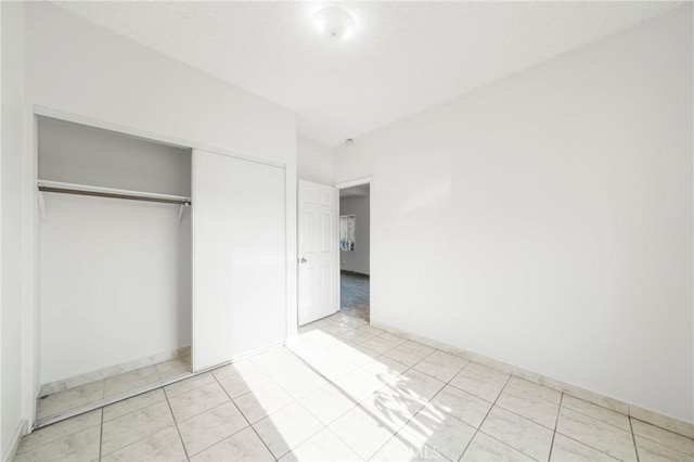 unfurnished bedroom featuring a closet and light tile patterned floors