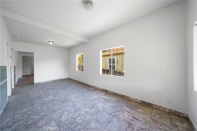 spare room with beamed ceiling and a textured ceiling