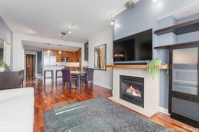 living room with track lighting, dark hardwood / wood-style flooring, and a fireplace