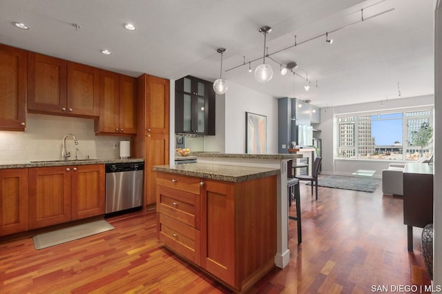 kitchen with dishwasher, a kitchen bar, sink, hanging light fixtures, and rail lighting