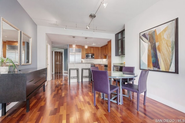 dining space with rail lighting and dark hardwood / wood-style flooring