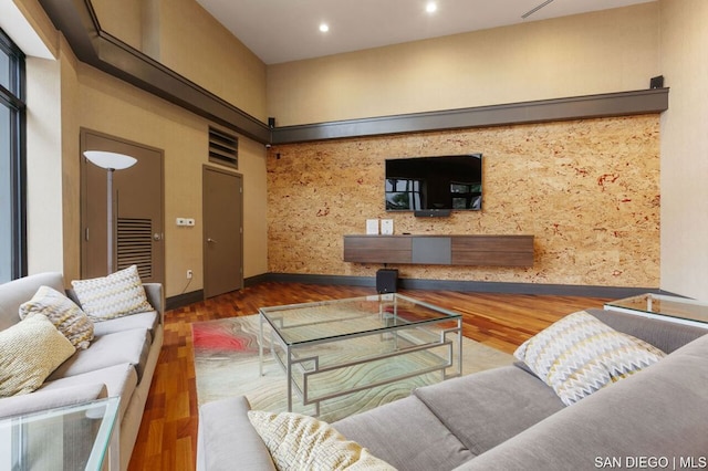 living room featuring hardwood / wood-style flooring and a towering ceiling