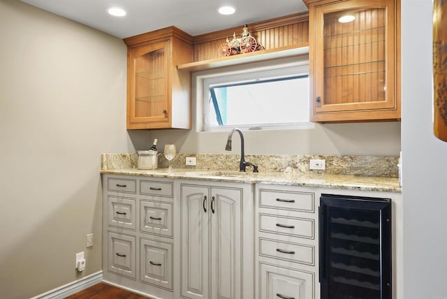 kitchen featuring sink, dark wood-type flooring, beverage cooler, and light stone counters