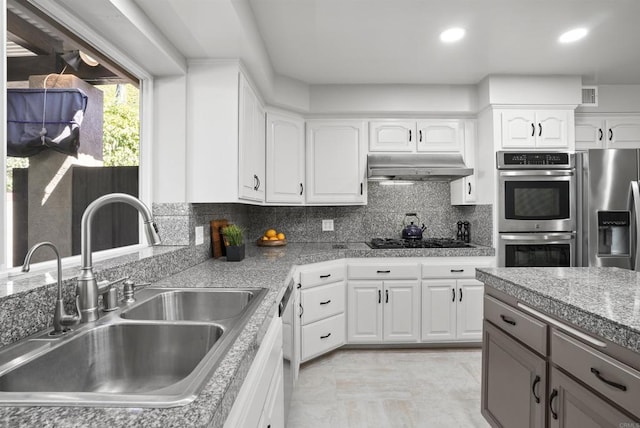 kitchen with tasteful backsplash, white cabinets, appliances with stainless steel finishes, and sink