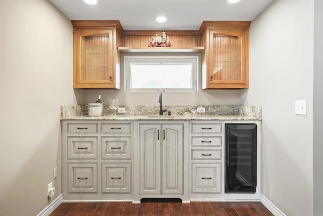 bar with light stone countertops, wine cooler, dark hardwood / wood-style floors, and sink