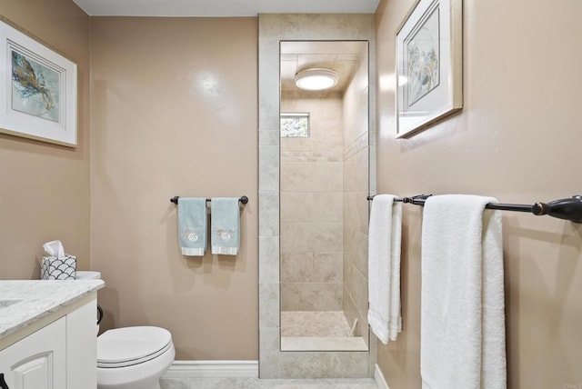 bathroom featuring toilet, vanity, and a tile shower